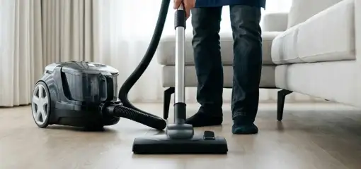 Professional house cleaner vacuuming a living room floor with a canister vacuum cleaner, Orlando, FL.