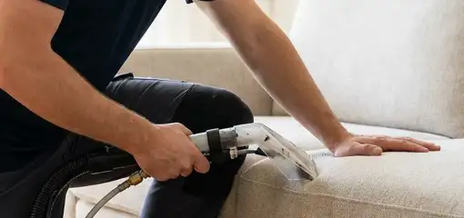 Professional upholstery cleaner deep-cleaning a fabric sofa with a handheld extraction tool, Orlando, FL.